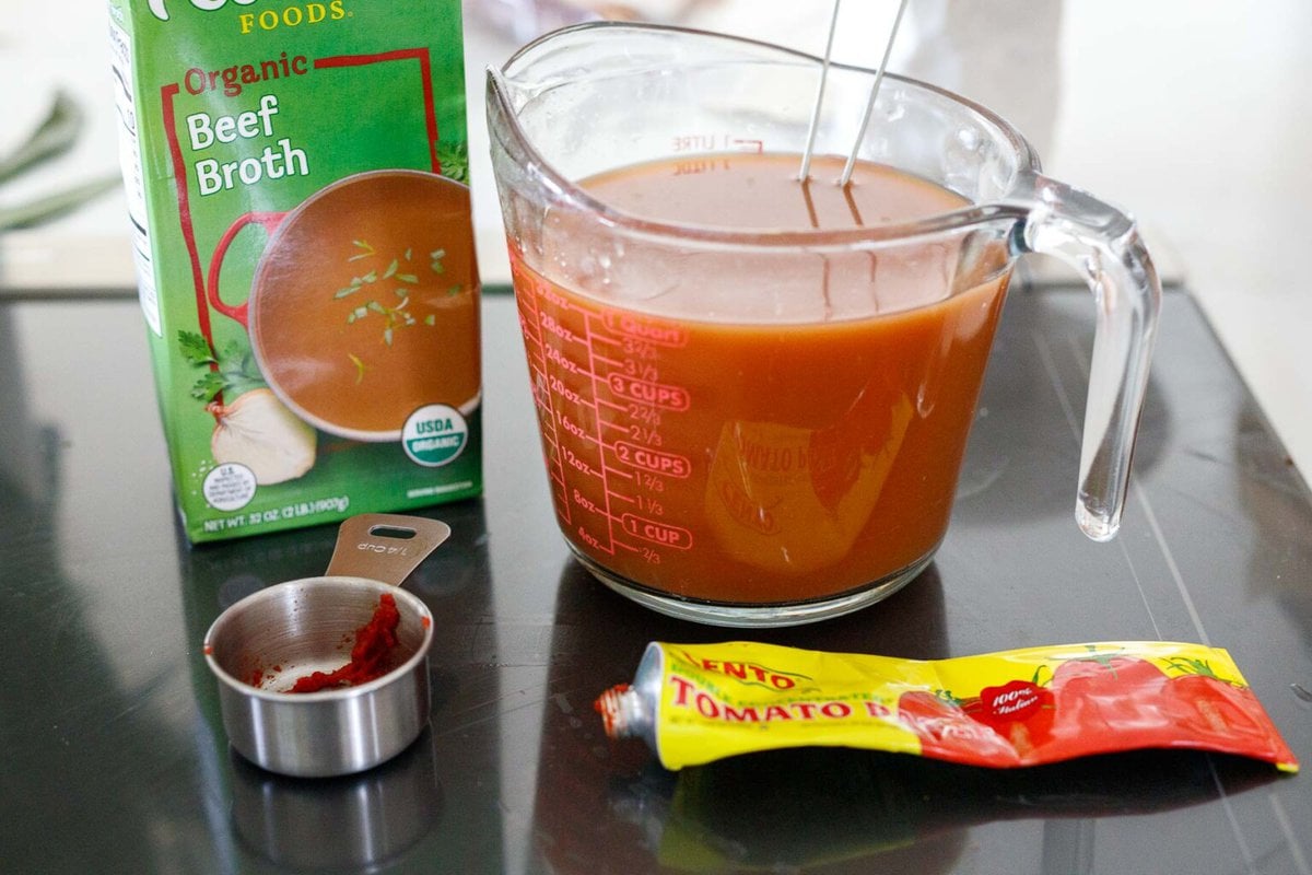 measuring cup with tomato paste and beef broth mixed together.