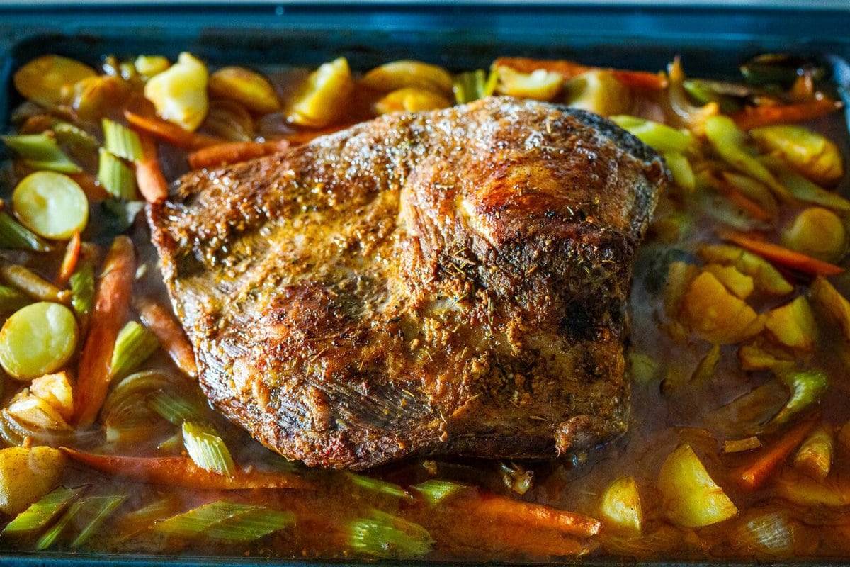 beef brisket cooked in roasting pan with veggies and stock.
