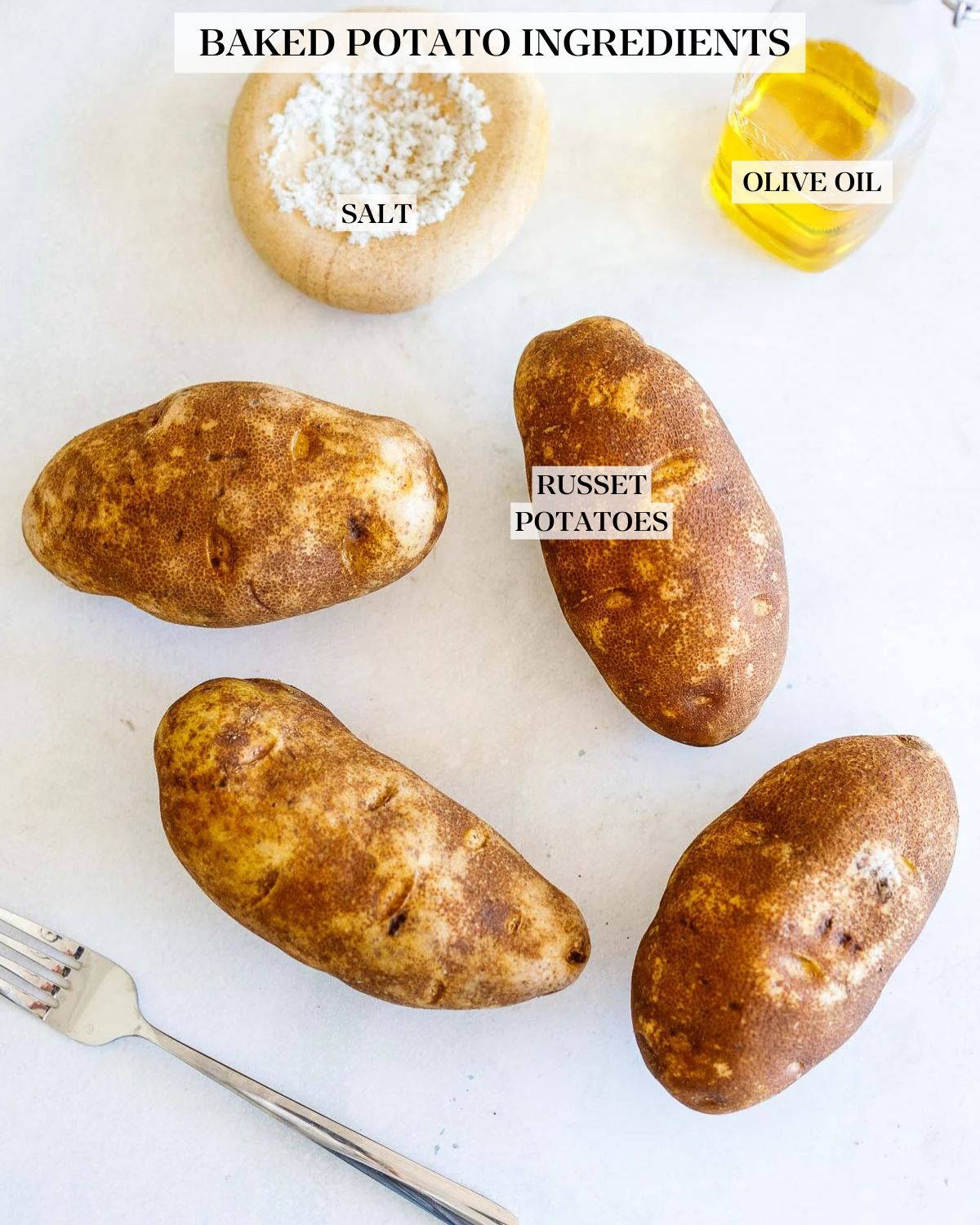 ingredients for baked potato - four russet potatoes surrounded by a fork, salt, and olive oil. 