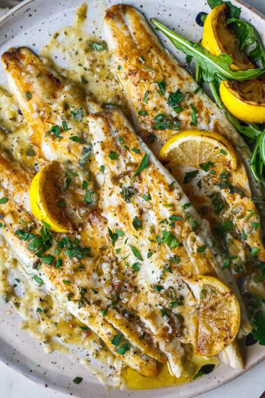 This easy branzino recipe is simply seasoned, pan-seared to perfection with crispy skin, and drizzled with a tangy lemon butter sauce.