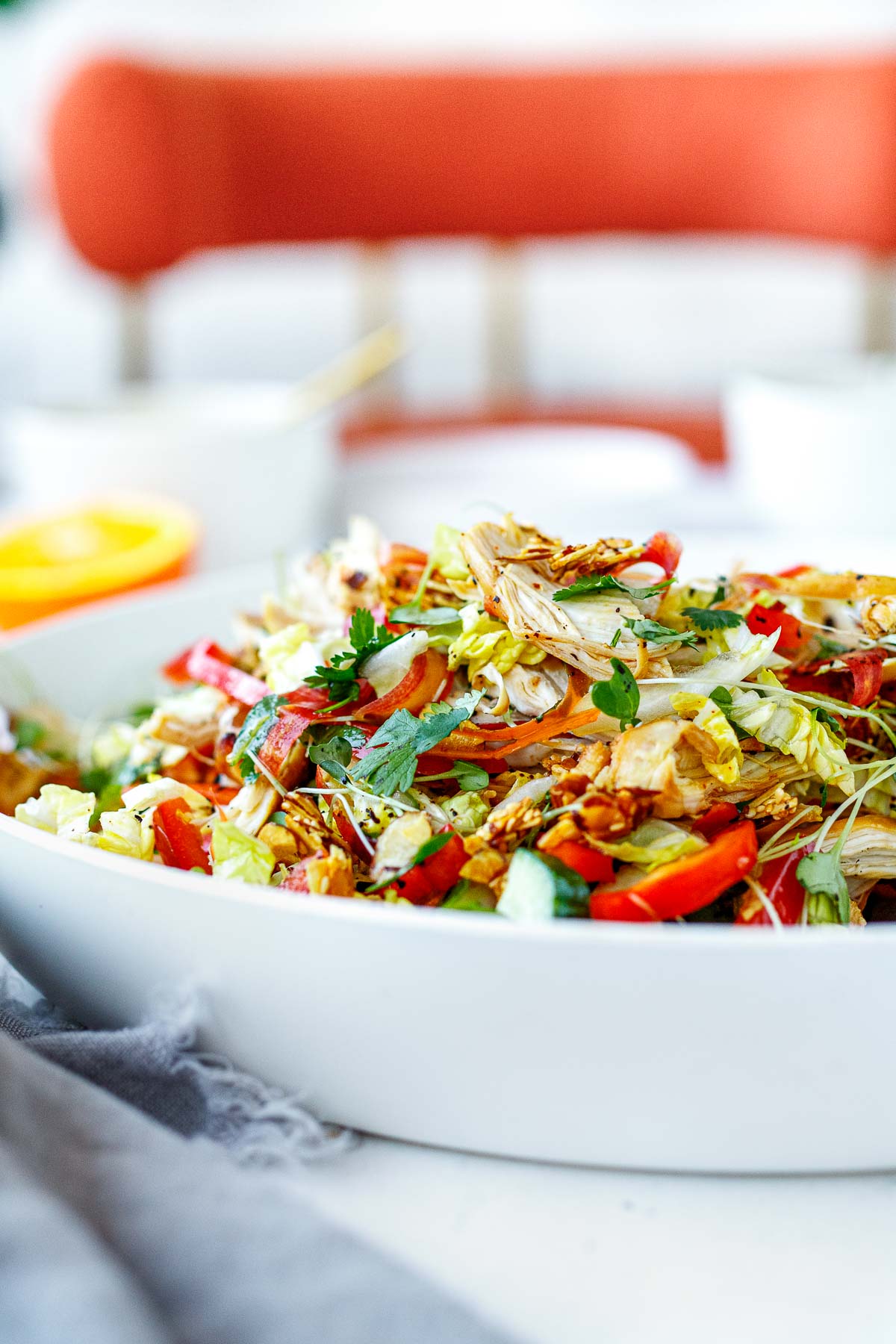 side view of the chinese chicken salad in a large bowl with shredded chicken.