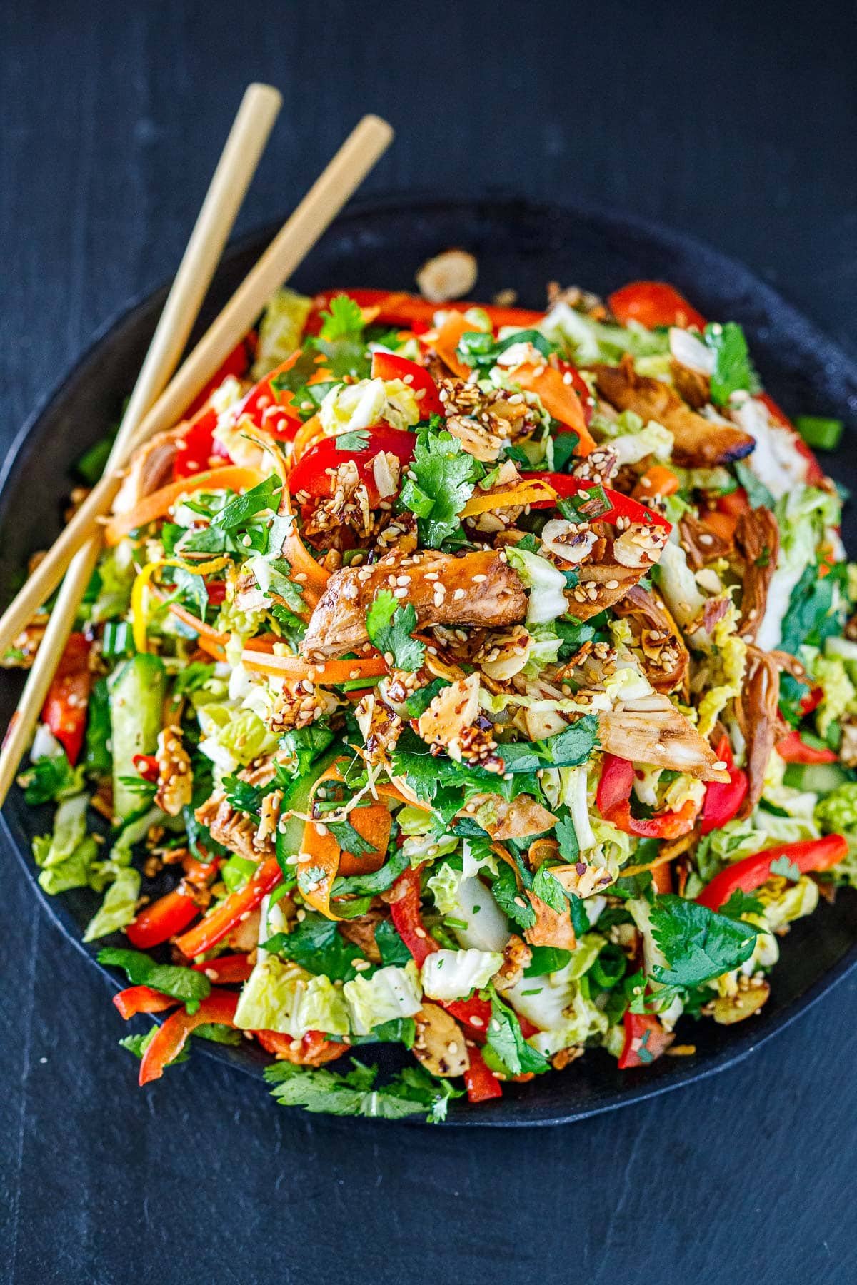 Chinese Chicken Salad, plated on a dark plate with chopsticks.