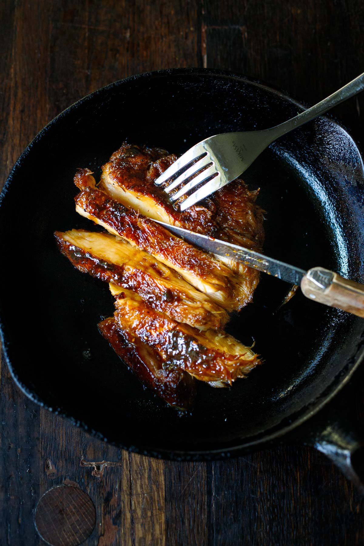 A tender succulent lions mane steak recipe, in a skillet being cut like a steak with a knife and fork. 