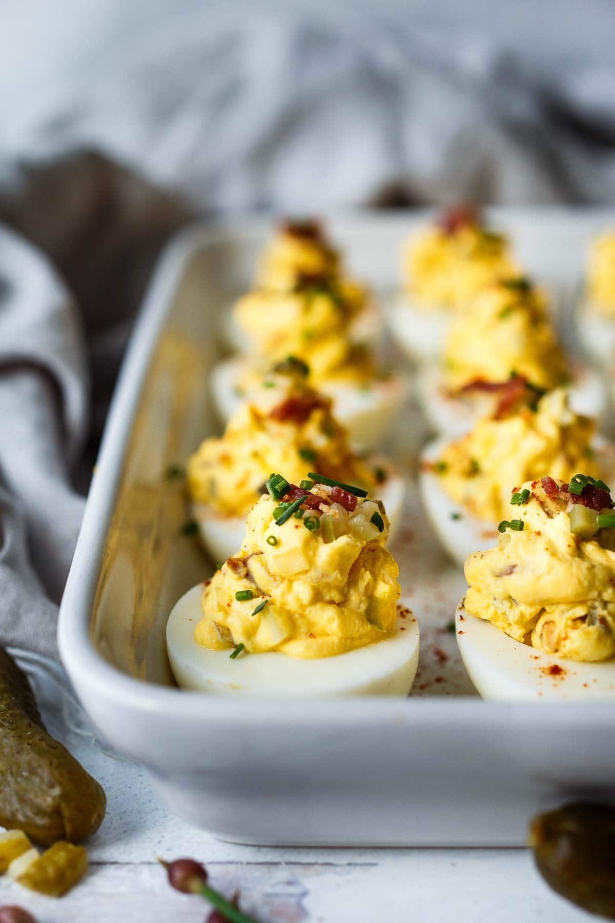 Deviled eggs are a classic appetizer, perfect for potlucks, gatherings, and holidays like Easter. Our deviled eggs recipe is creamy and delicious, studded with crispy bacon (or vegan bacon), aged cheddar cheese, diced pickles, and sweet onions. A crowd-pleasing, low-carb appetizer that everyone will love!