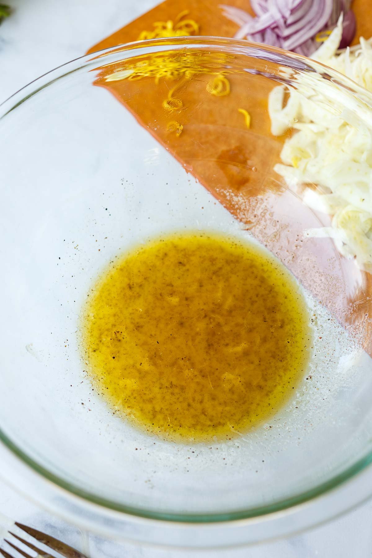 glass mixing bowl with dressing for white bean salad. 
