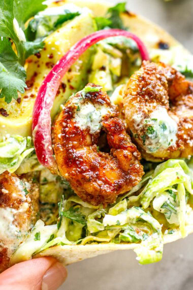 Spicy, flavorful shrimp tacos with fresh cilantro lime slaw, avocado, pickled onions and cilantro lime crema - a delicious and easy weeknight meal! Gluten-free adaptable.