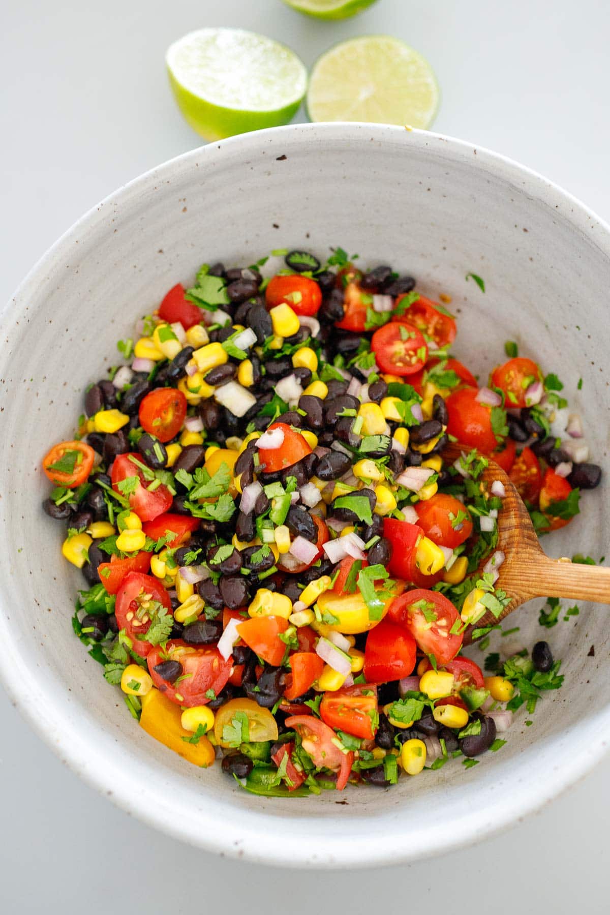 black bean salsa in mixing bowl with wood spoon to stir.