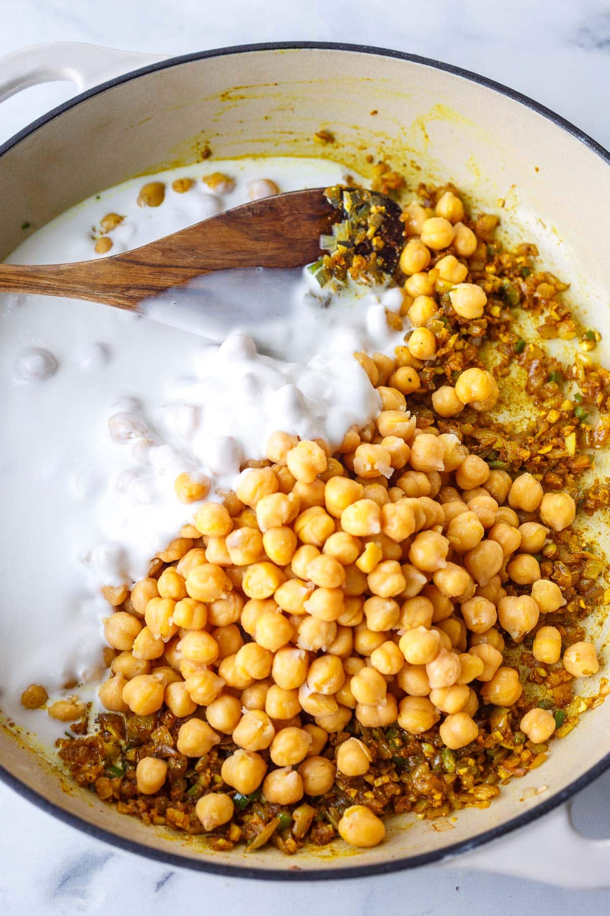 large pan with coconut milk, chickpeas, and spiced aromatics to make chickpea curry.