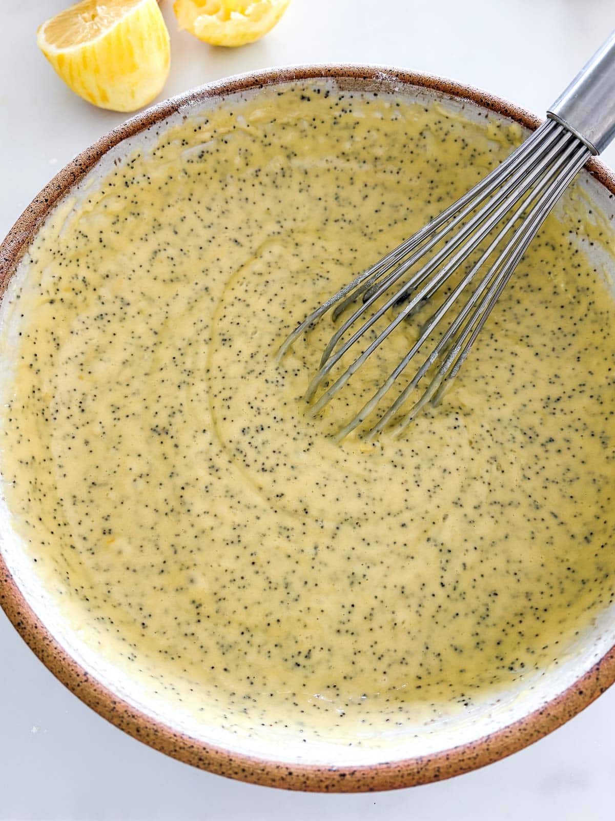 mixing bowl with lemon poppy seed cake batter and whisk.