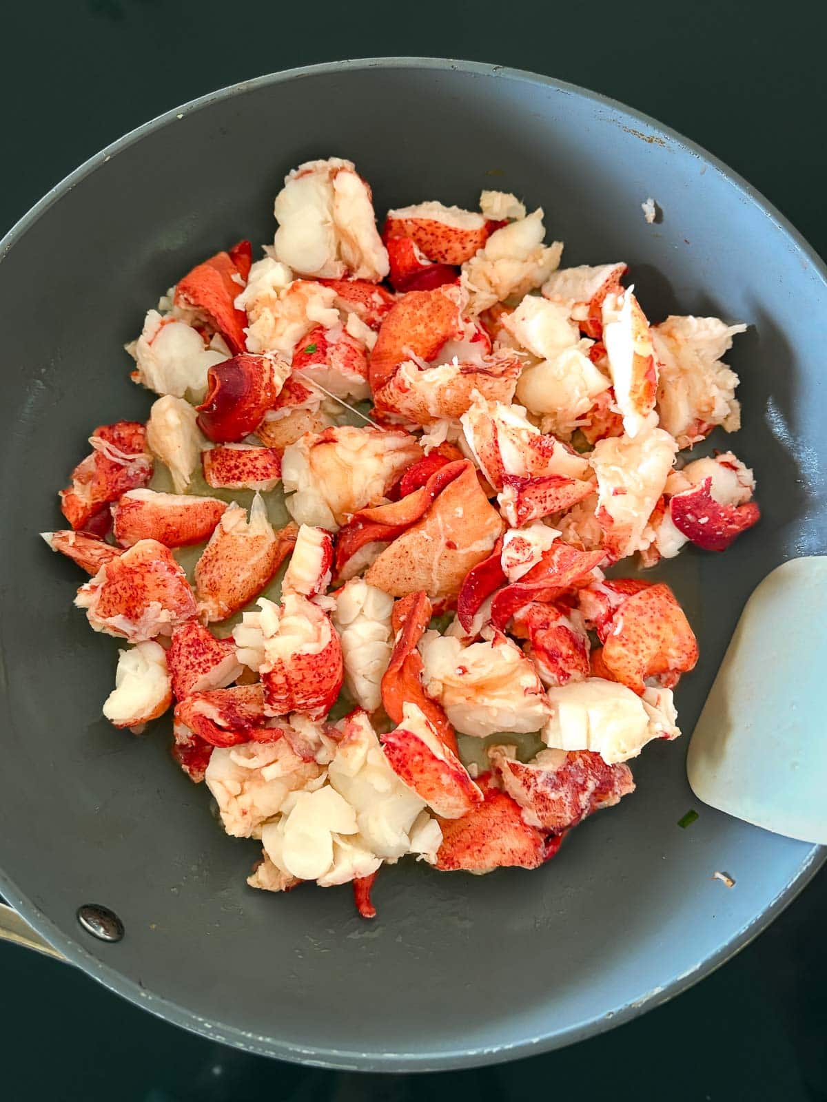 skillet with lobster pieces gently warming in butter.