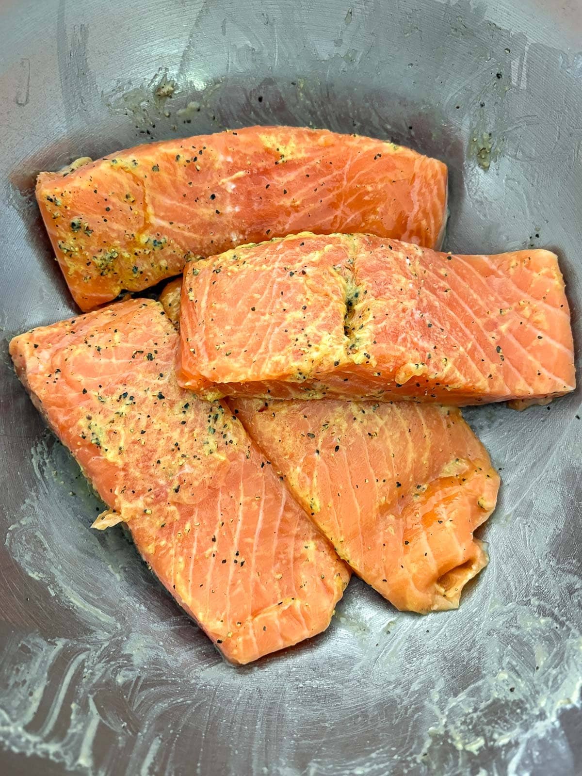 seasoned salmon filets coated with dijon in bowl.