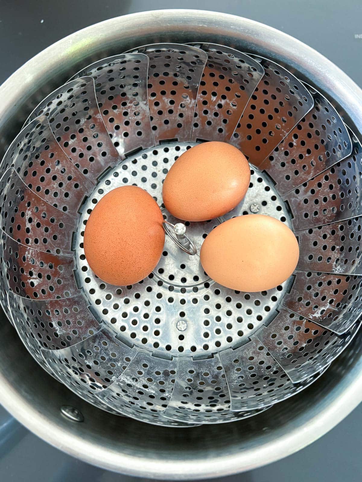 three eggs in steamer basket.