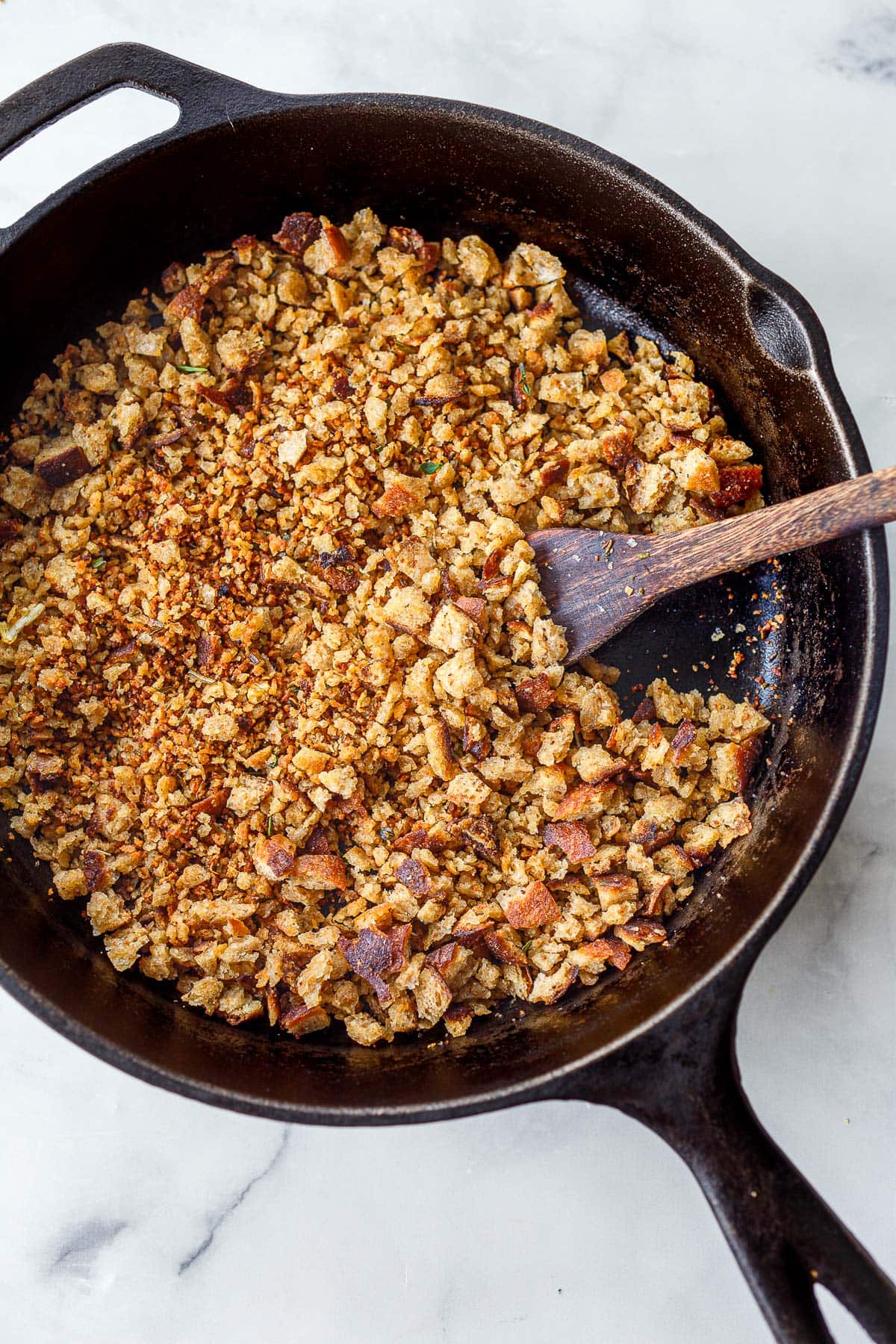 toasted pangrattato in cast iron skillet with wood spoon.
