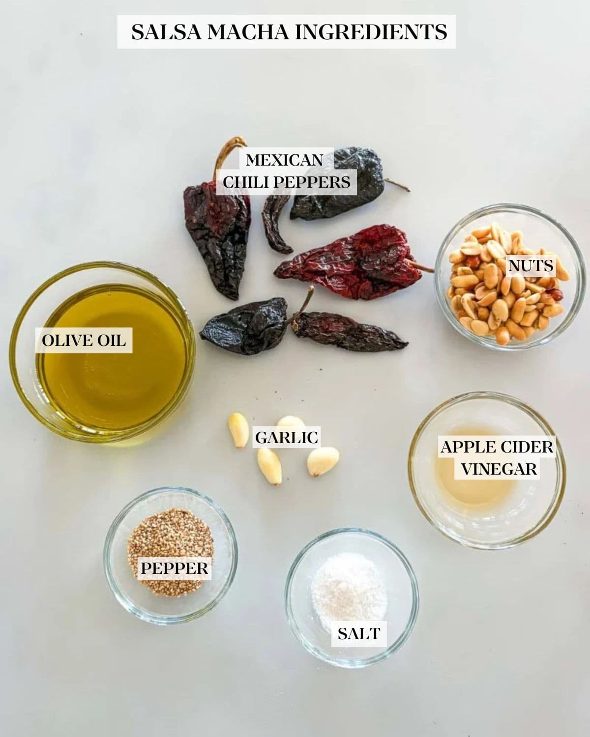 Salsa macha ingredients on a white counter- dried Mexican chile pepper, oil, peanuts, garlic, sesame seeds, salt and vinegar. 