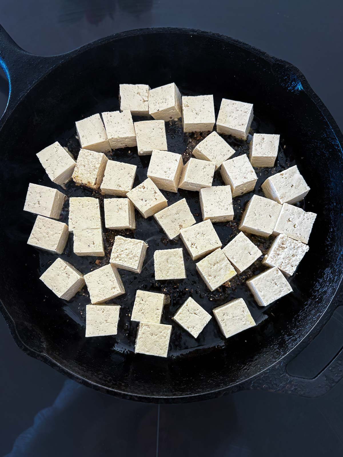 cubed tofu in cast iron skillet spread out evenly.