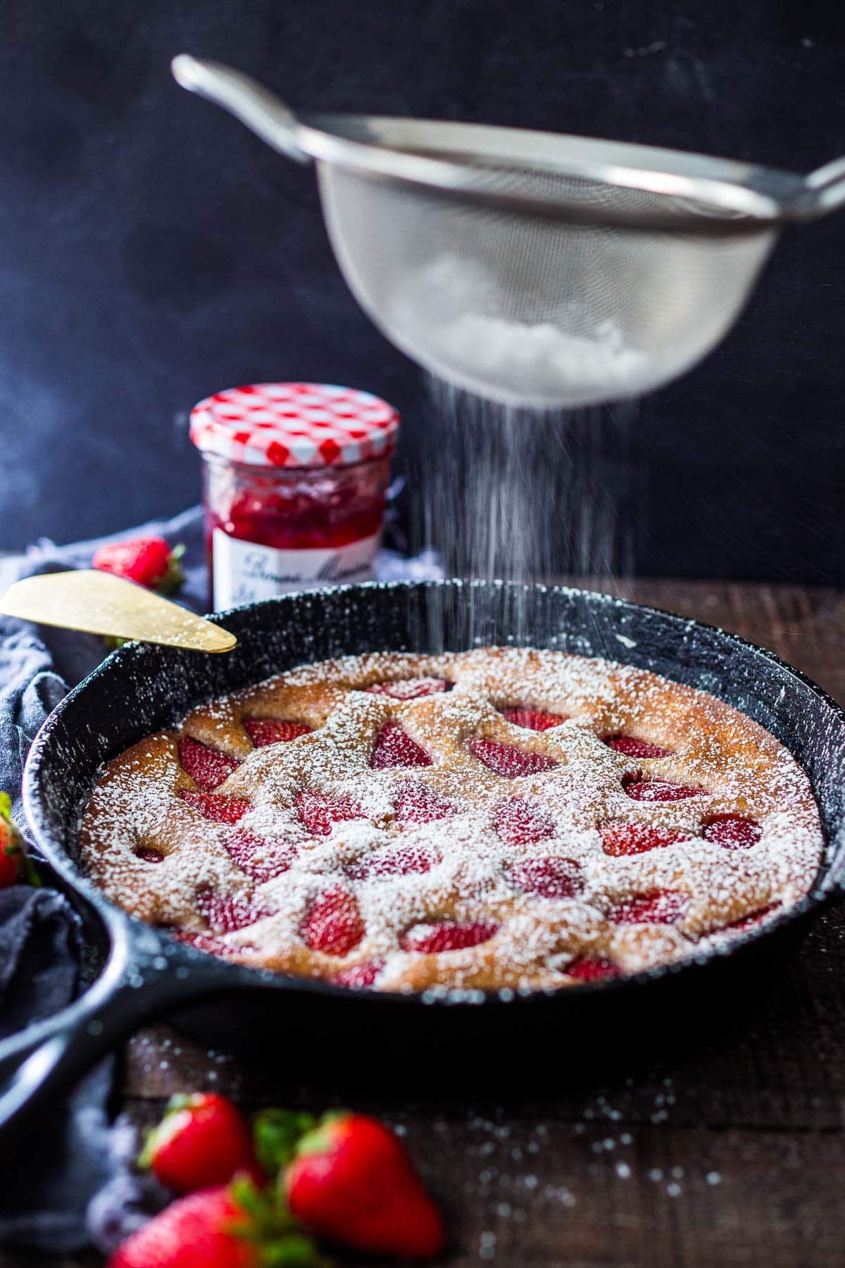 Sprinkling powdered sugar over the cake. 