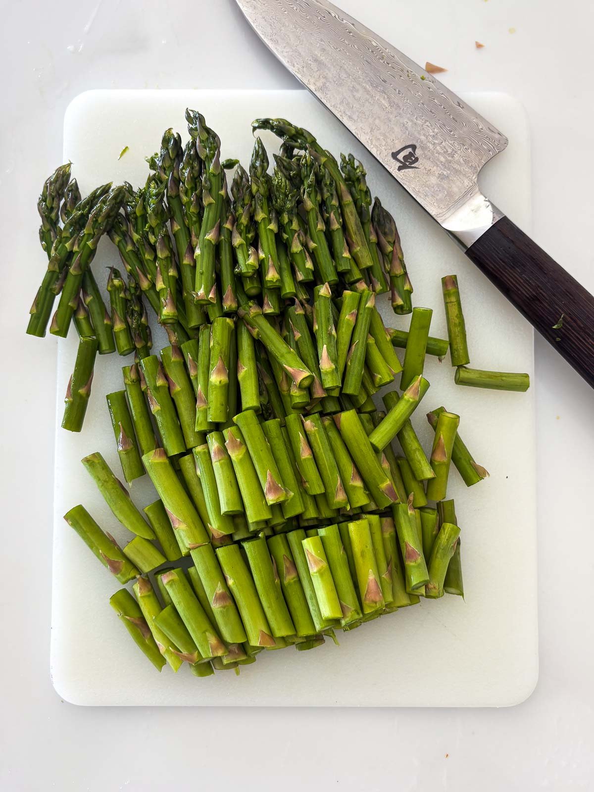 sharp knife and trimmed and cut asparagus on cutting board.