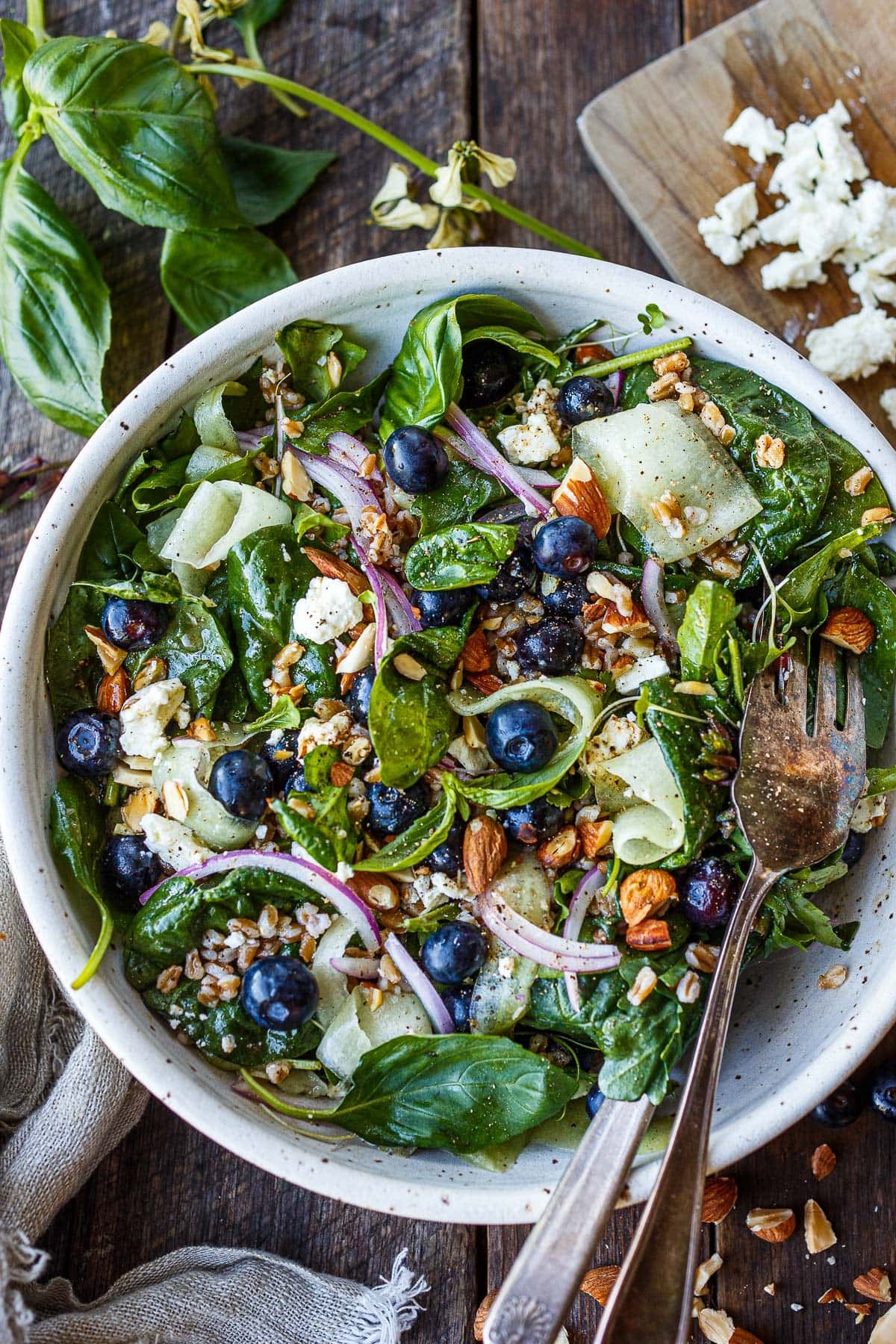blueberry spinach salad with shaved cucumber, blueberries, almonds, farro, sliced red onion, and feta. 