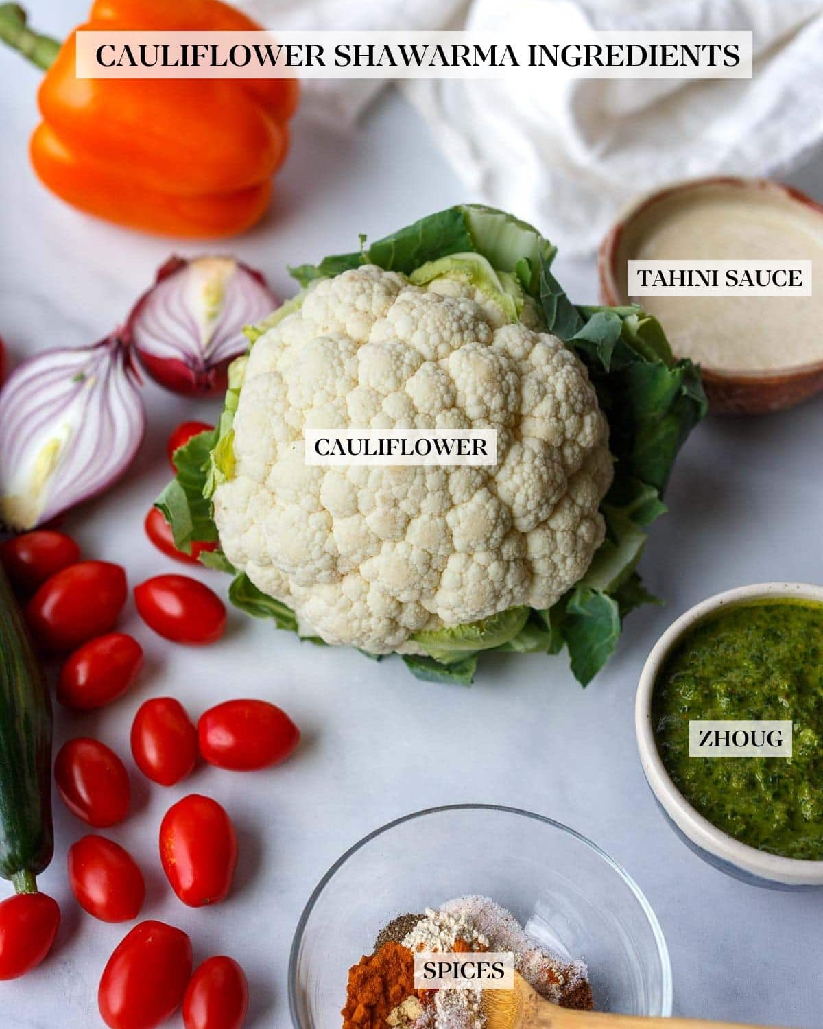 ingredients for cauliflower shawarma- cauliflower head, onion, tomato, cucumber, tahini sauce, zhoug, shawarma spice blend.