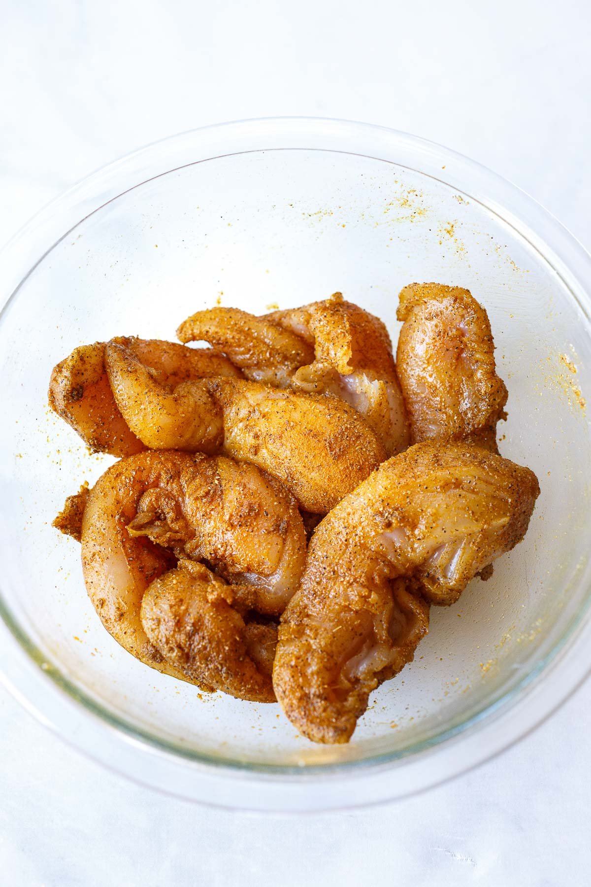 glass bowl of chicken coated in shawarma spice marinade. 