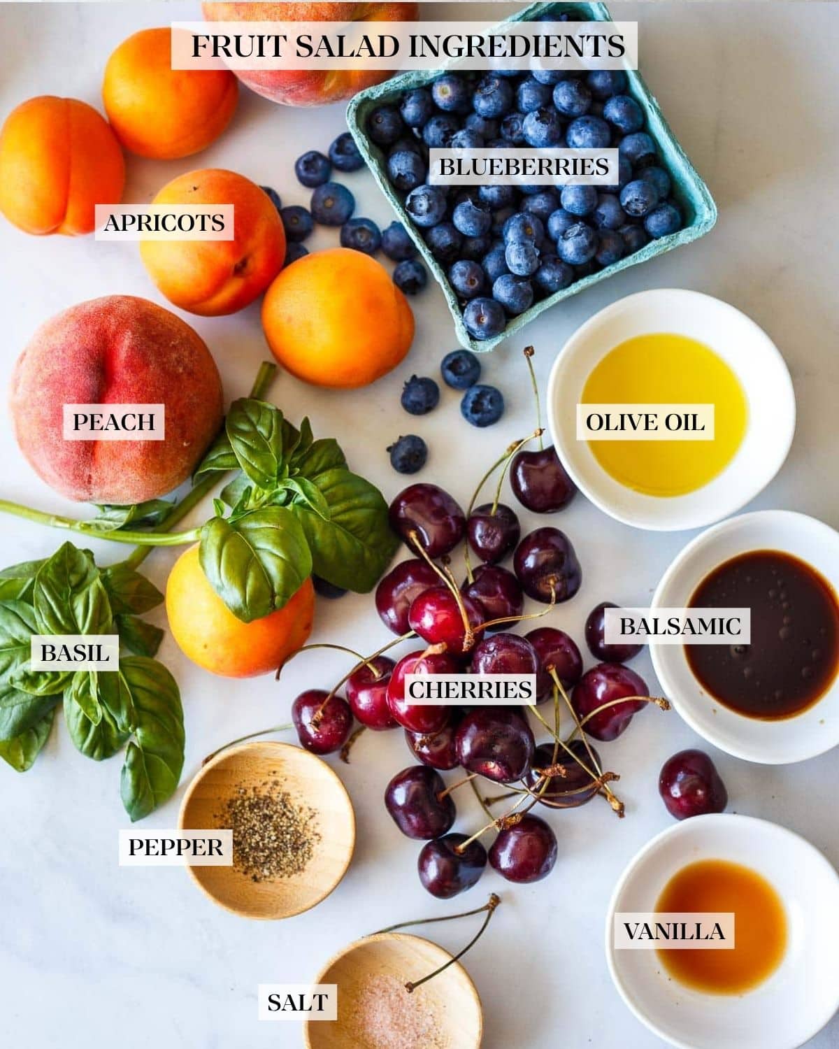 Ingredients laid out: blueberries, olive oil, balsamic vinegar, vanilla, salt, pepper, cherries, basil peach, apricots.