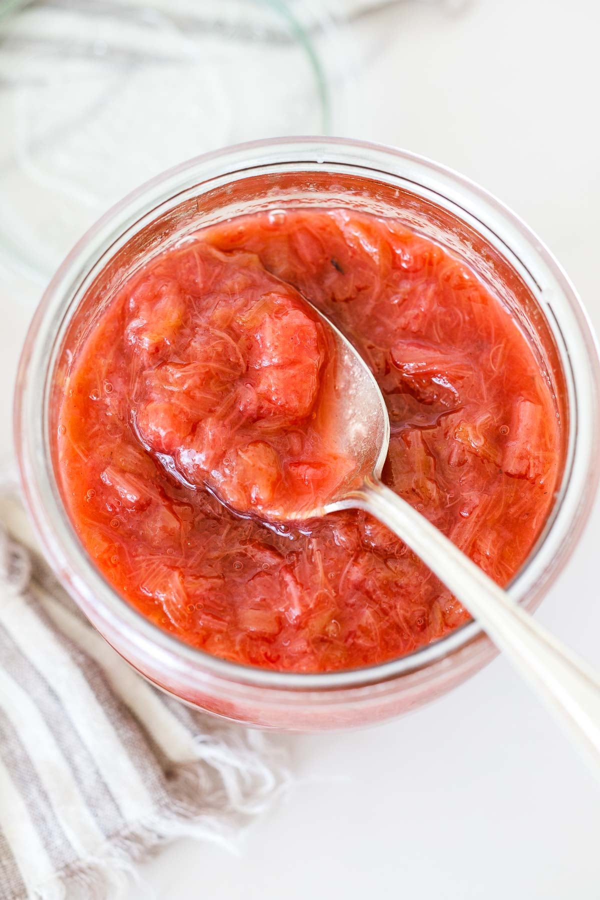 glass jar of rhubarb compote with a spoon.