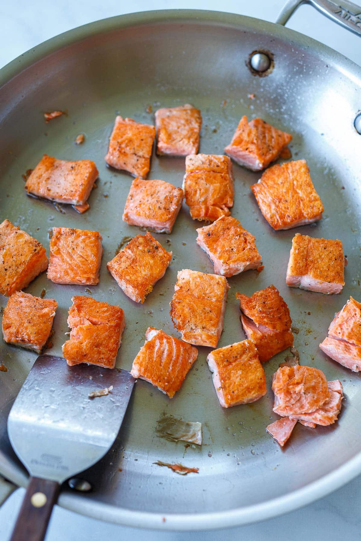 Salmon cube browning in a saute pan.