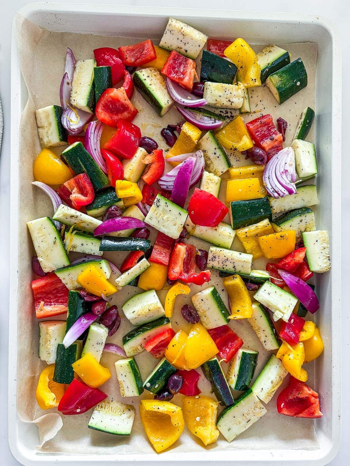 sheet pan full of mediterranean veggies that are marinated.