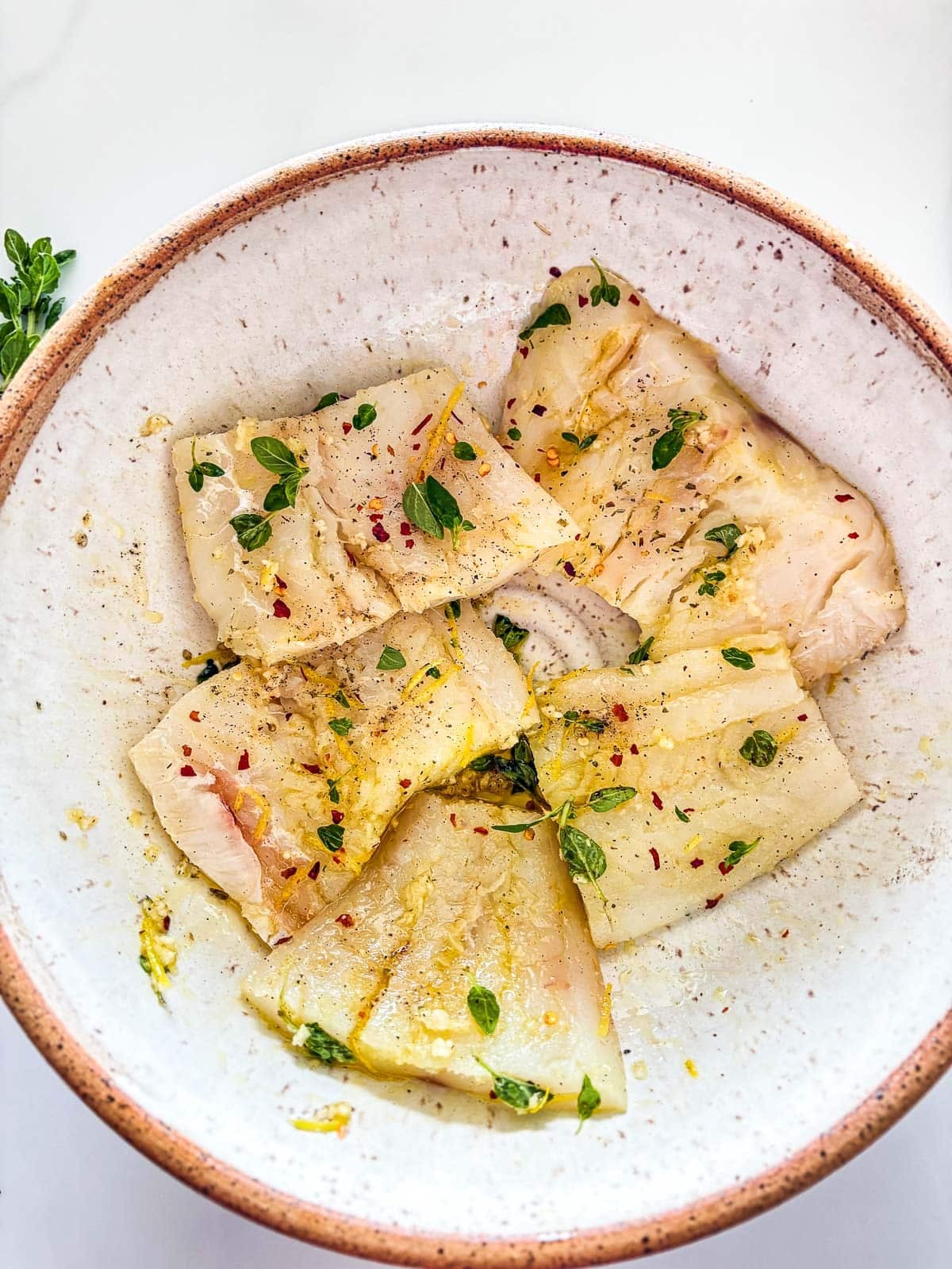 in the same bowl, marinate the cod with olive oil, lemon zest, salt, pepper and chili flakes.