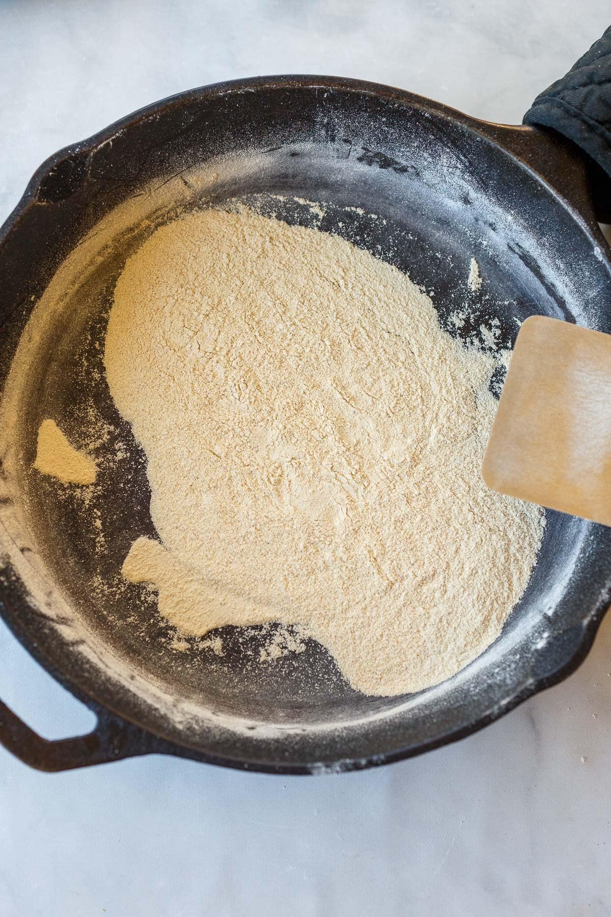 rice flour toasting in dry skillet with wooden spatula. 