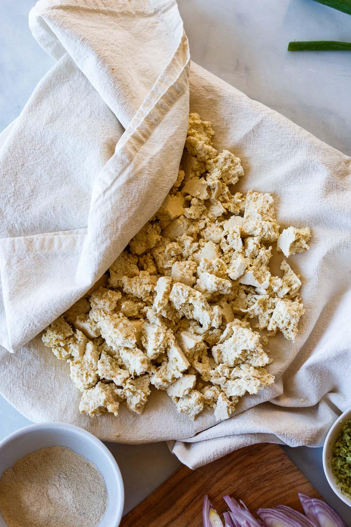 crumbled tofu on kitchen towel, partially folded over to dry.