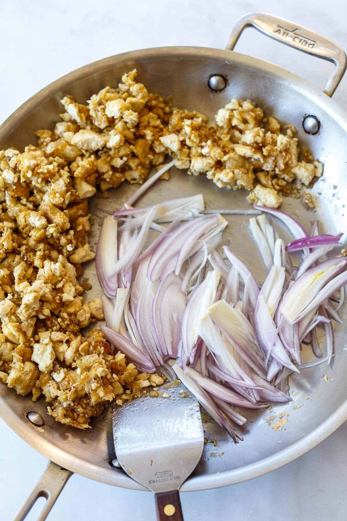 Cooked tofu and shallots in pan.
