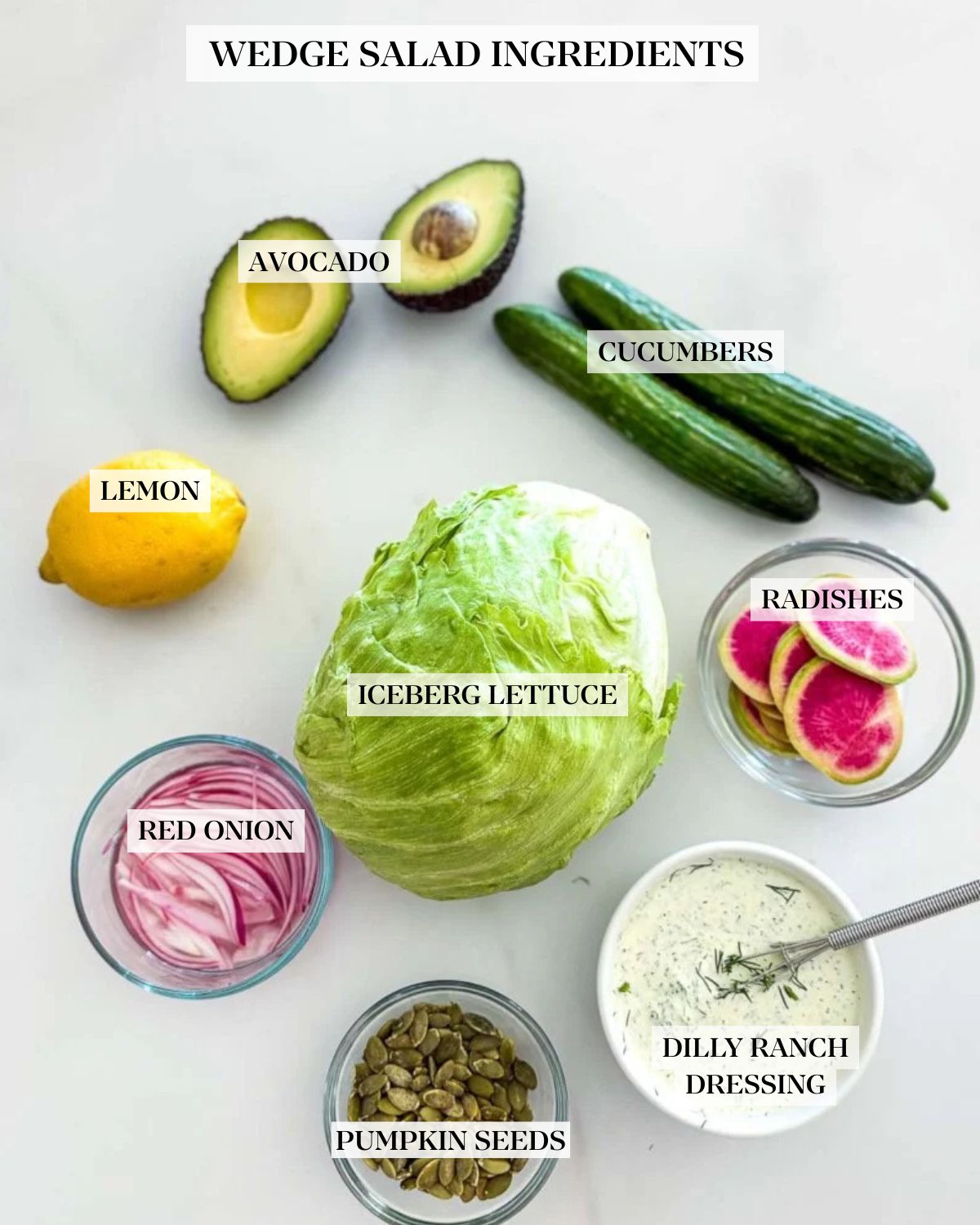 ingredients laid out for wedge salad - avocado, cucumber, watermelon radish, dilly ranch dressing, iceberg lettuce, pepitas, red onion, and lemon. 