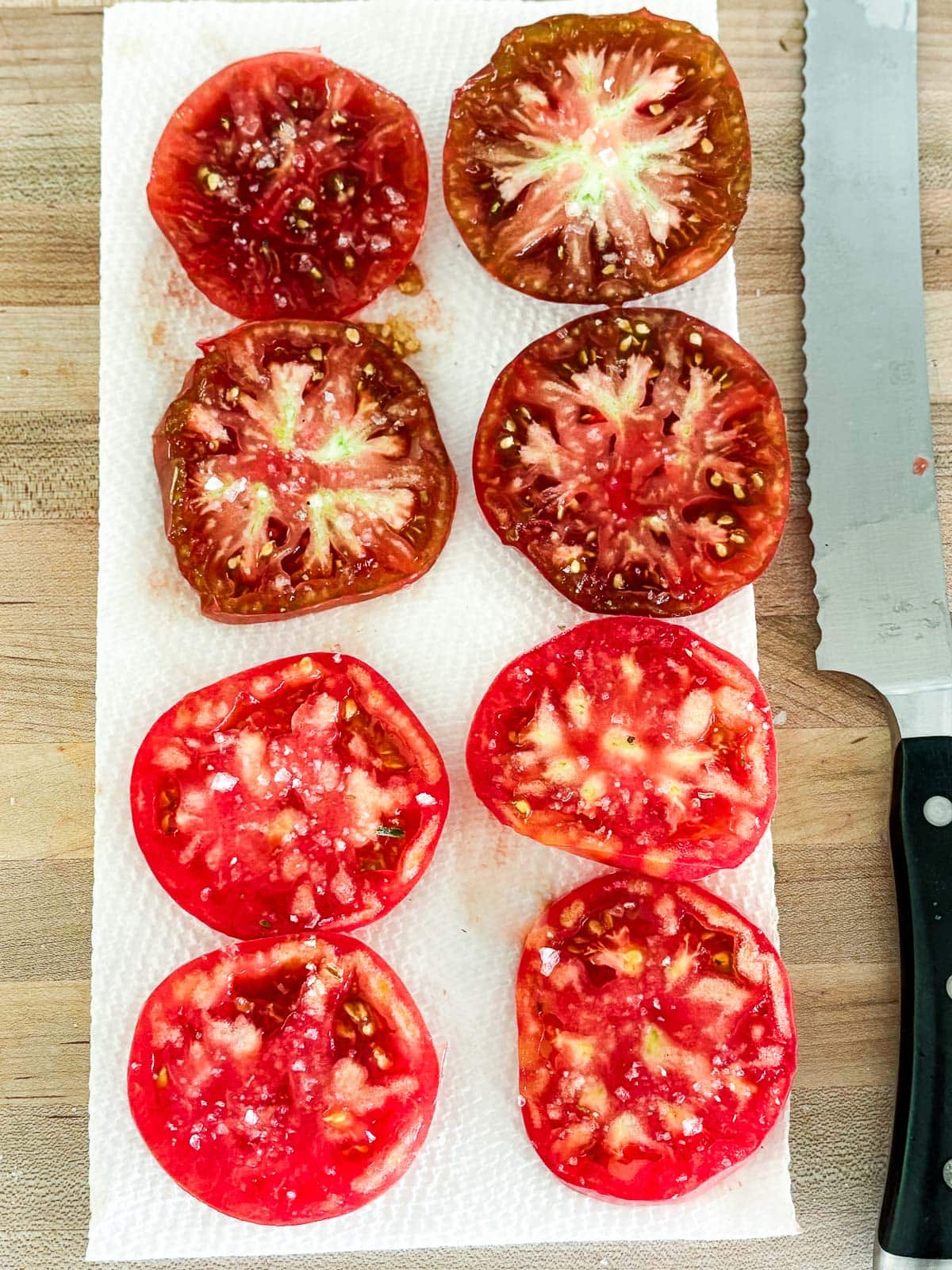 salted tomatoes resting on paper towels. 