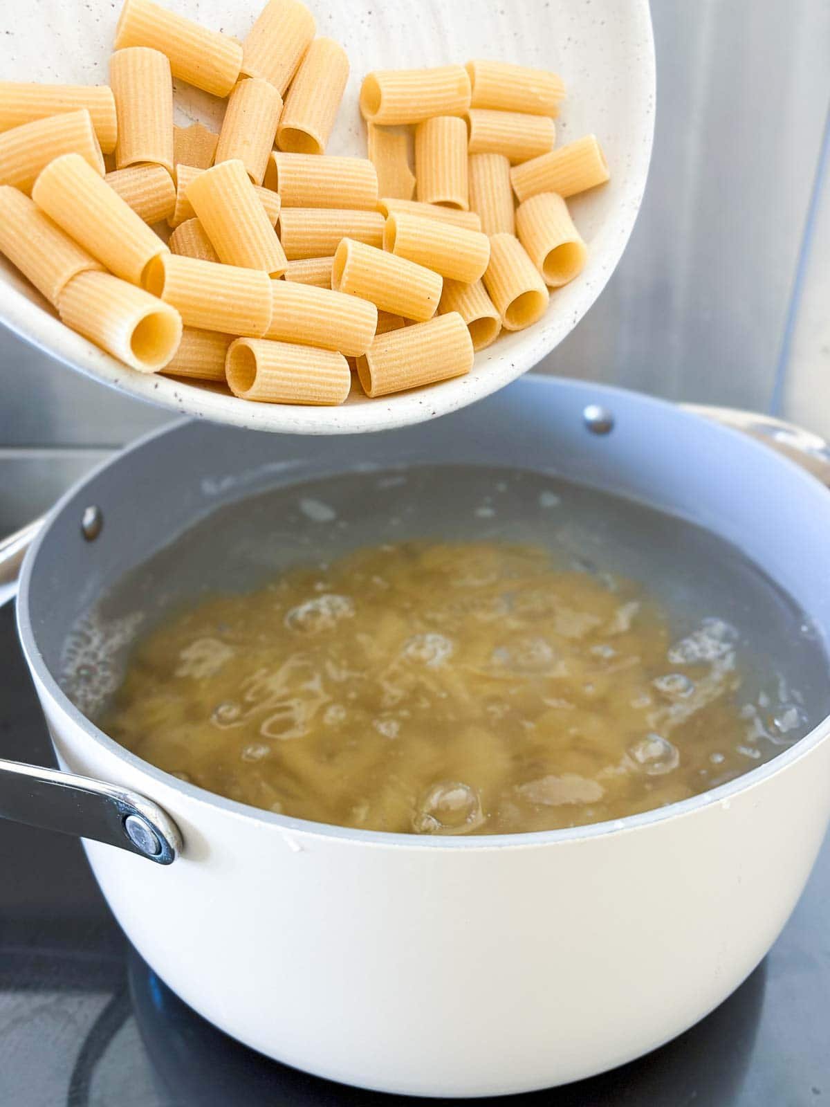 pouring dry pasta into pot of boiling water. 