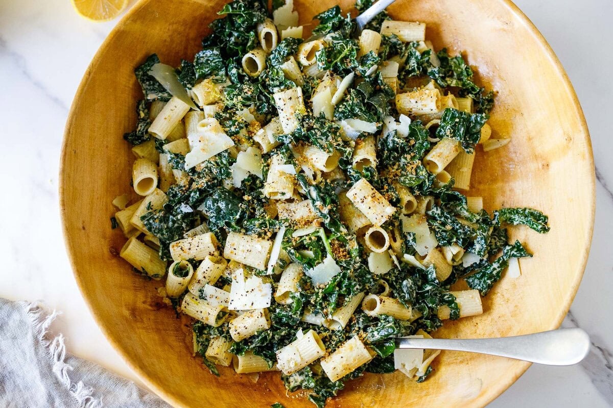 wood bowl with kale caesar pasta salad with pecorino, pepper, and chili flakes. 