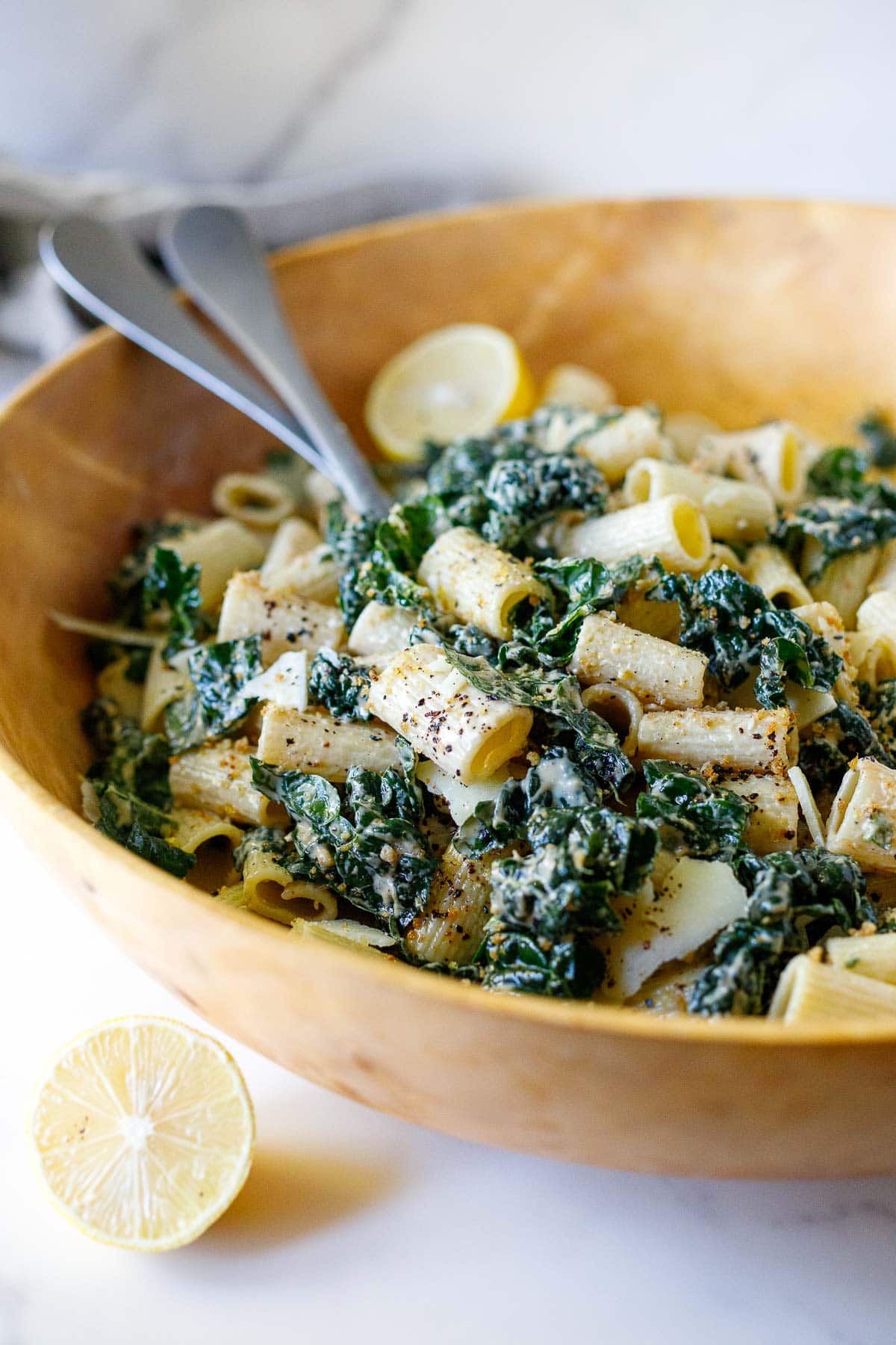 kale caesar pasta salad in bowl, topped with toasted breadcrumbs, red pepper flakes, and pecorino. 