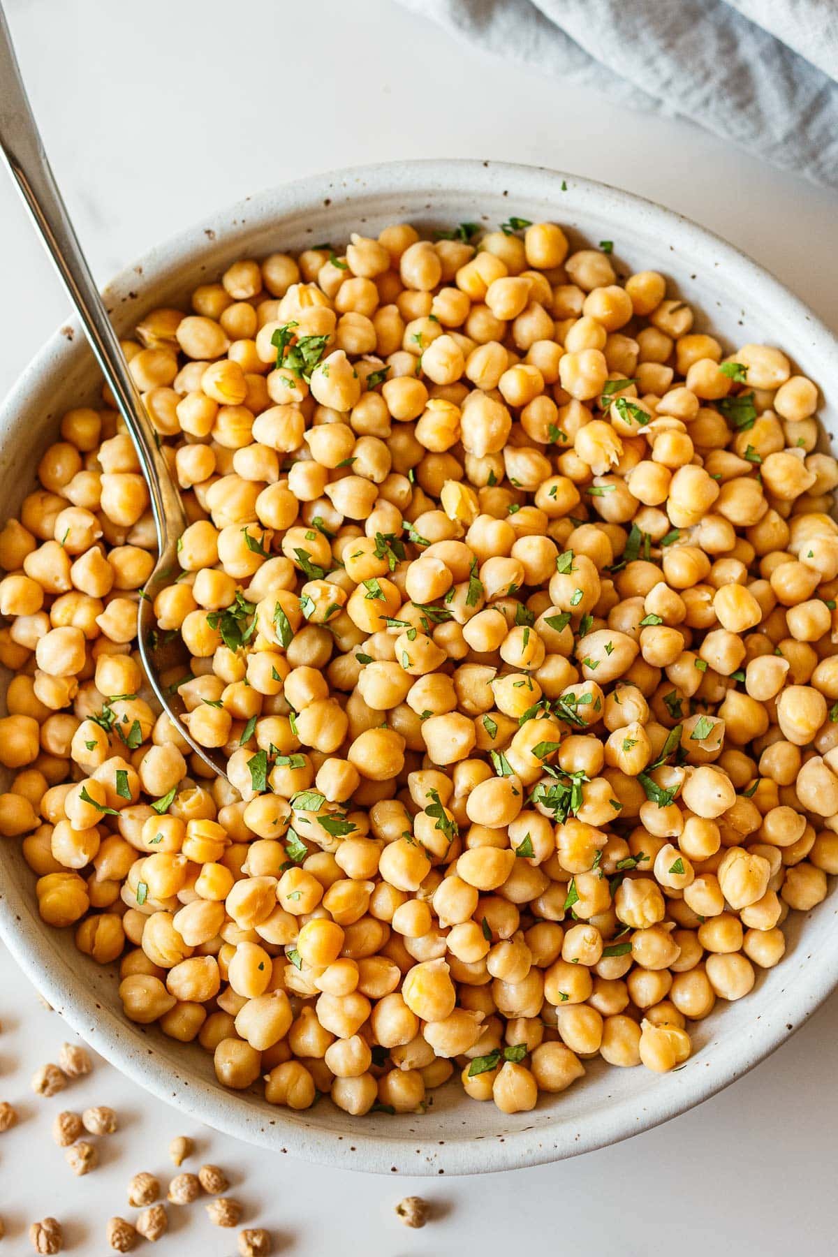 fresh chickpeas cooked from scratch in a bowl with fresh parsley and a spoon.