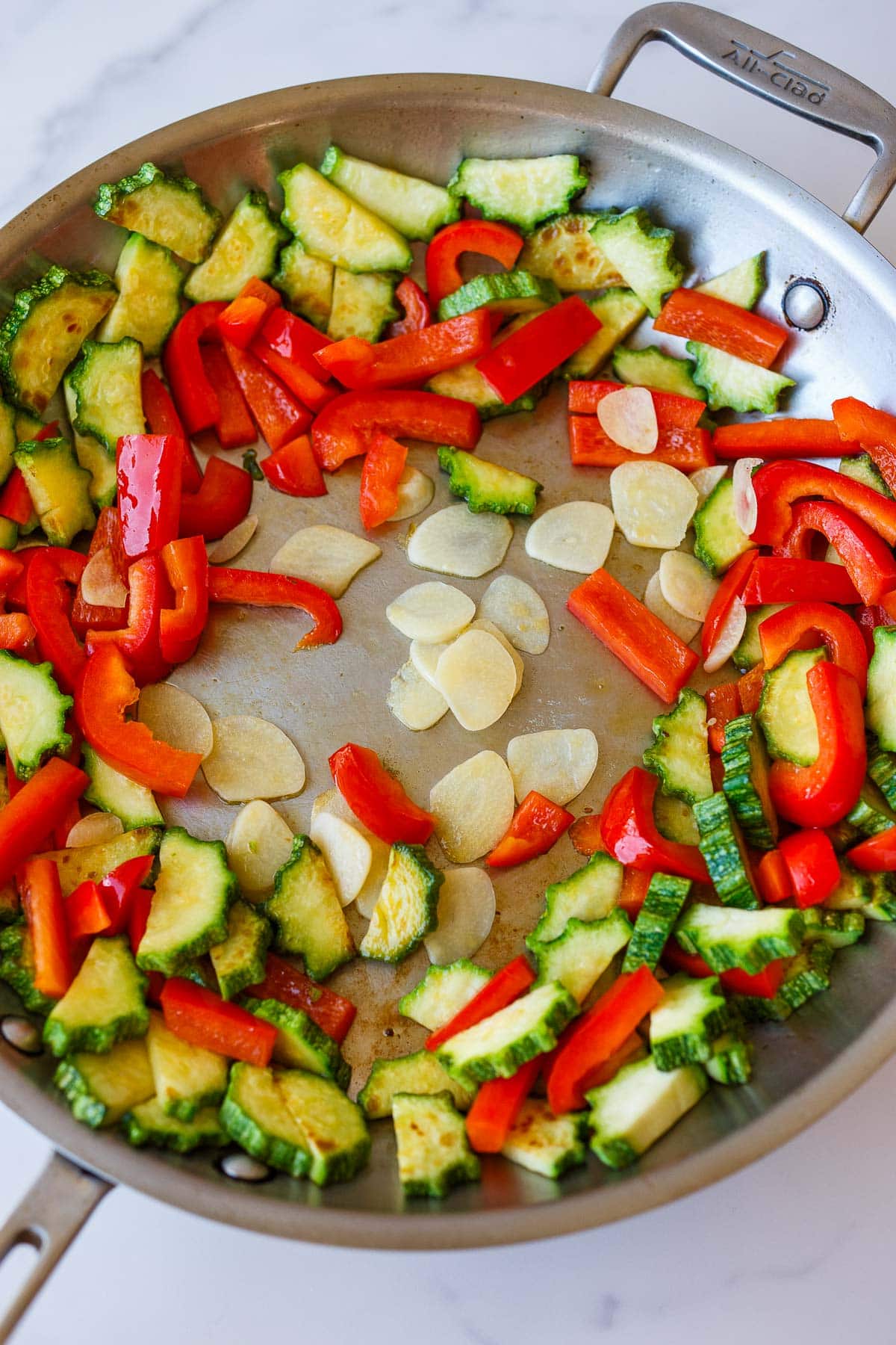 stainless steel skillet with sauteed zucchini, bell peppers, and garlic.