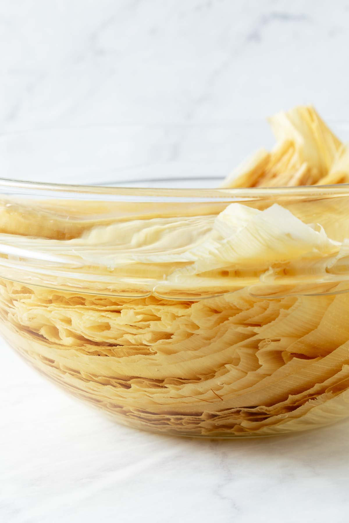 large glass bowl with corn husks soaking in water. 