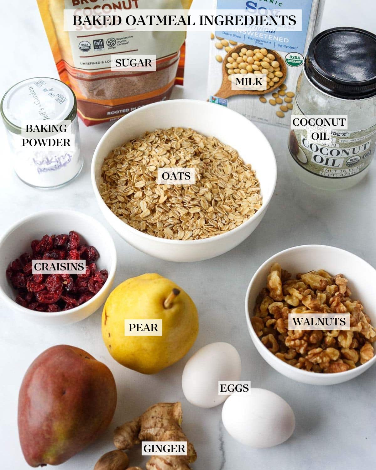 ingredients for baked oatmeal on marble surface - oats, walnuts, dried cranberries, pears, eggs, ginger, baking powder, brown sugar, soy milk, coconut oil