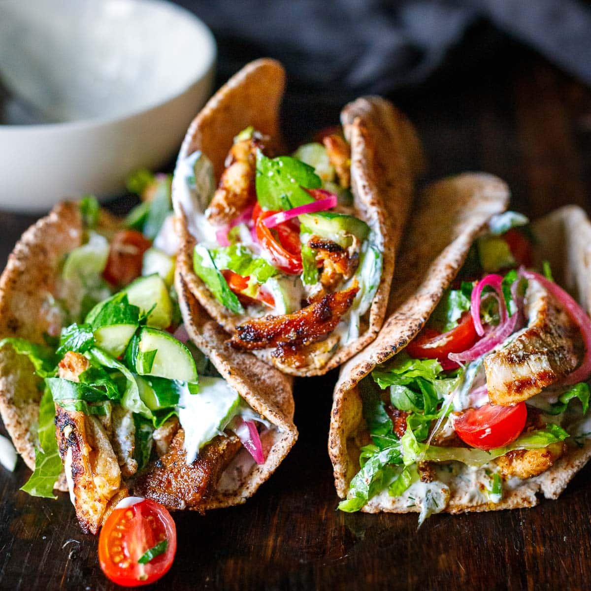 This easy Chicken Gyros recipe is packed with authentic Greek flavor! Tender succulent chicken is cooked to perfection, then tucked into warm pita bread with tzatziki, tomatoes, cucumbers, and onions. Vegetarian-adaptable!
