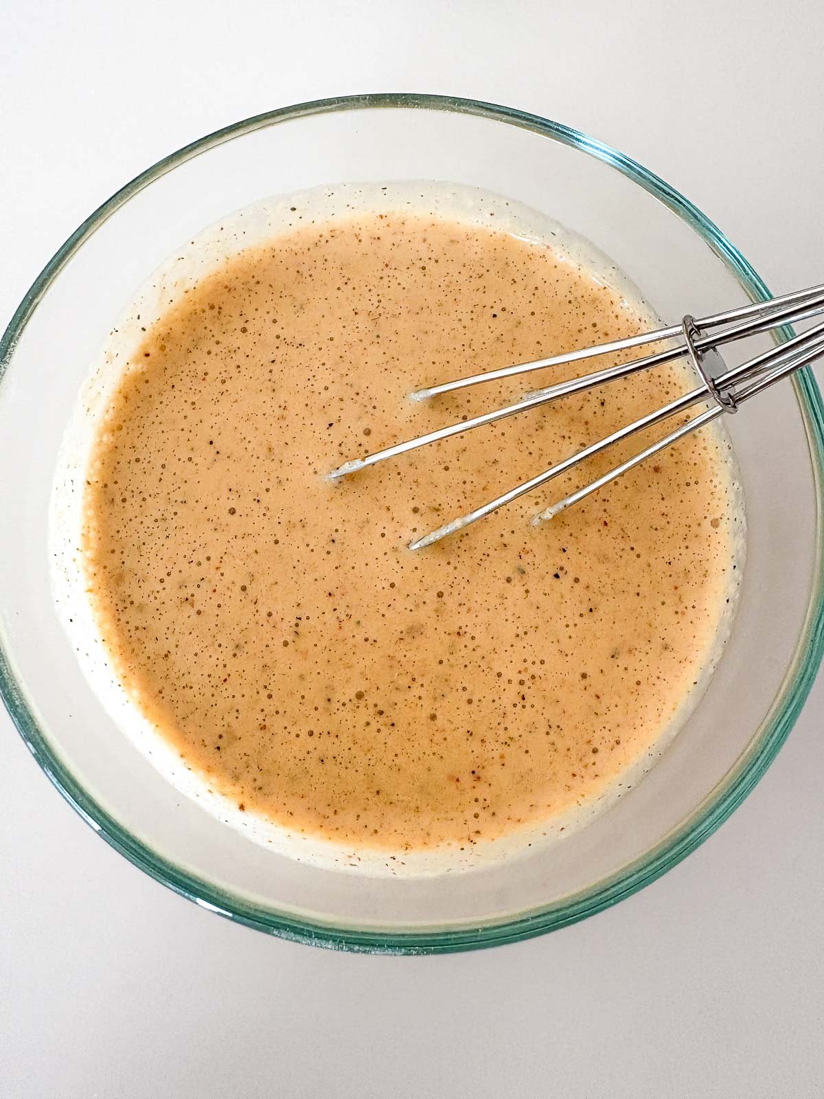 glass bowl and whisk with chicken gyro marinade. 