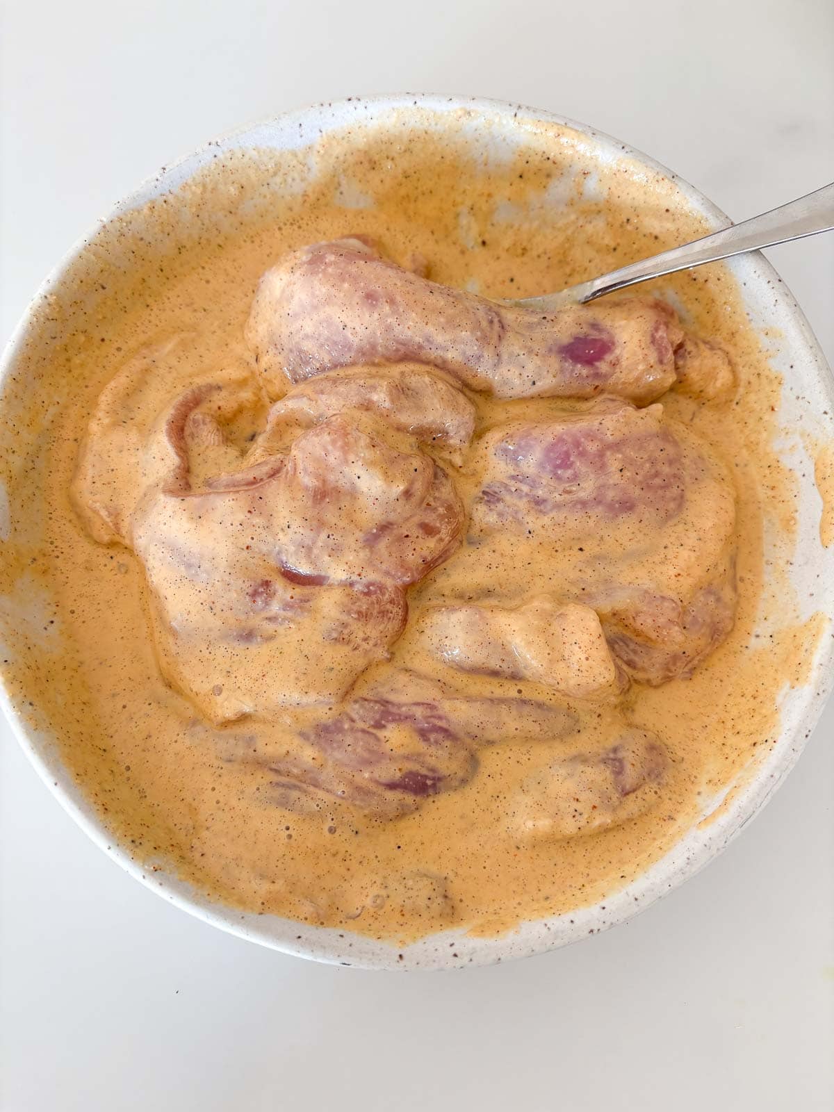 chicken thighs marinating in bowl for chicken gyros. 