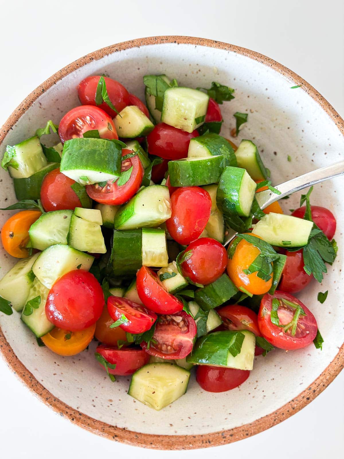 ceramic bowl with tomato cucumber salad with parsley.