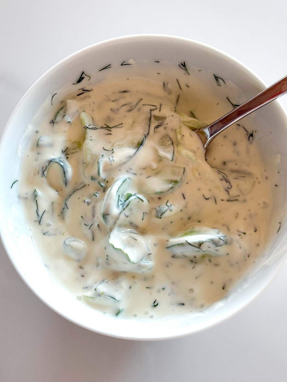 white bowl with tzatziki sauce with spoon. 