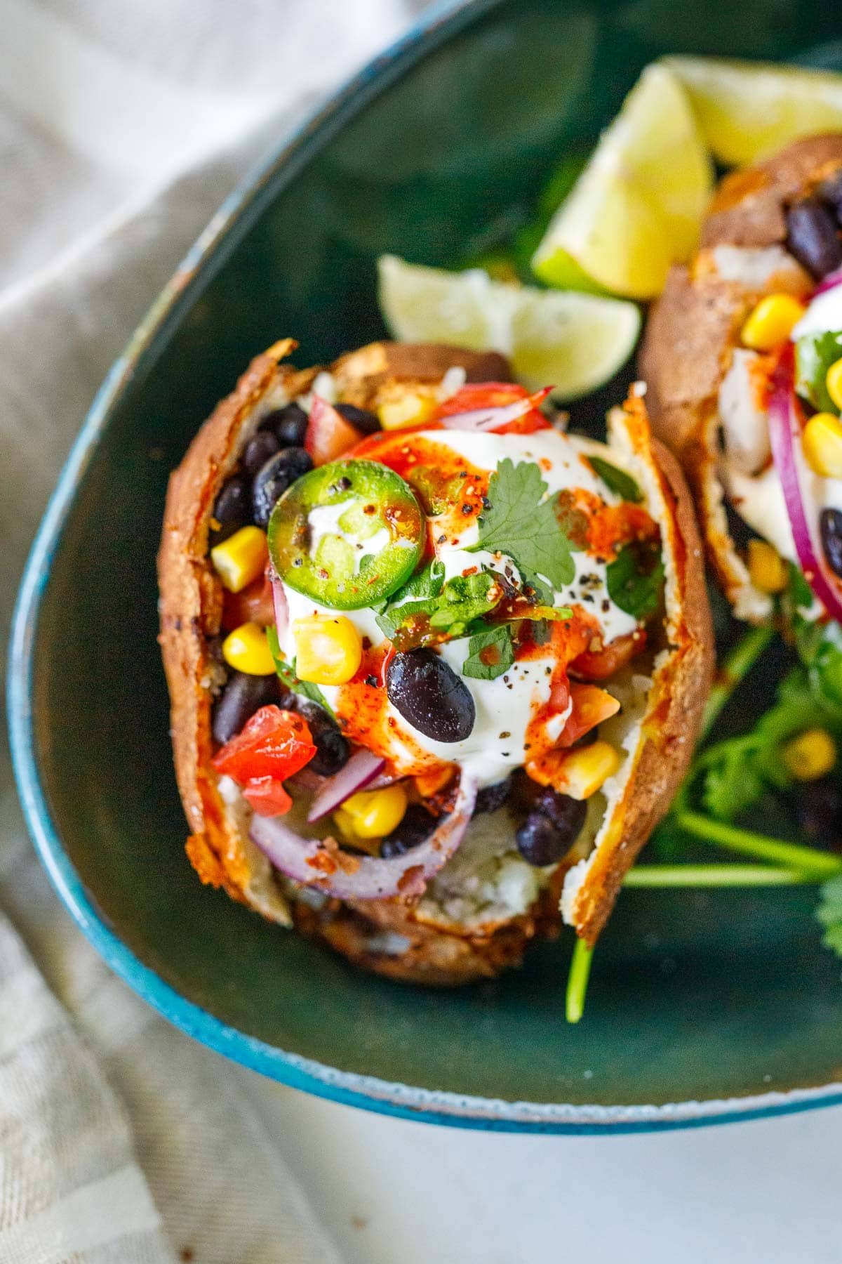 Mexican Baked Potatoes, stuffed with black beans and veggies topped with cilantro, jalapeno and sour cream.