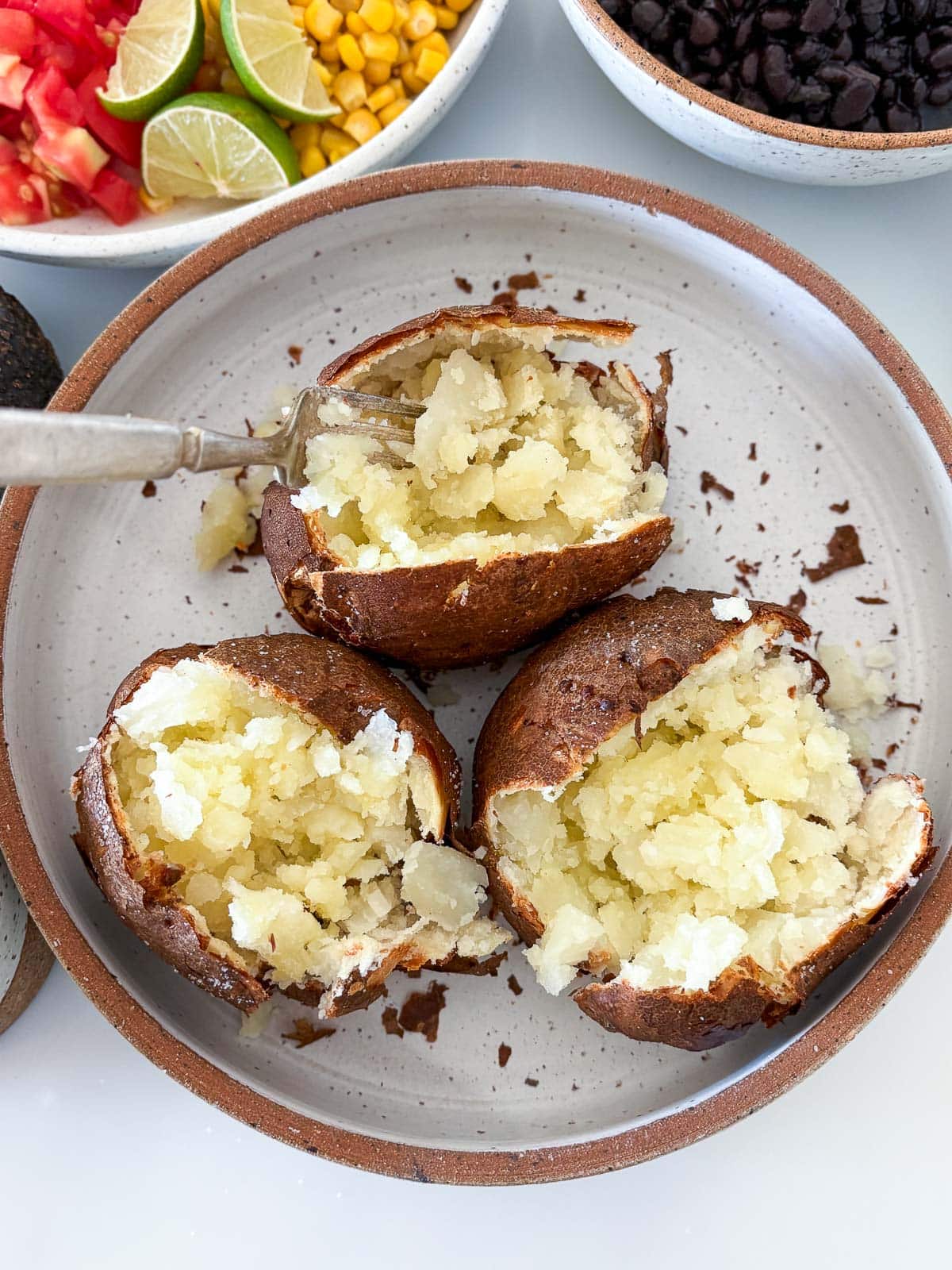 Fluffing the baked potatoes with a fork and seasoning.