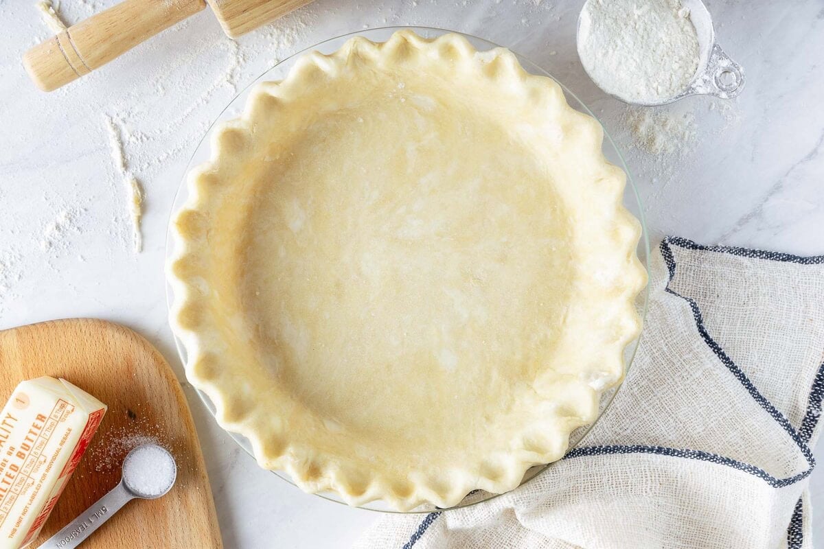 pie crust in a glass pie pan with crimped edges. 