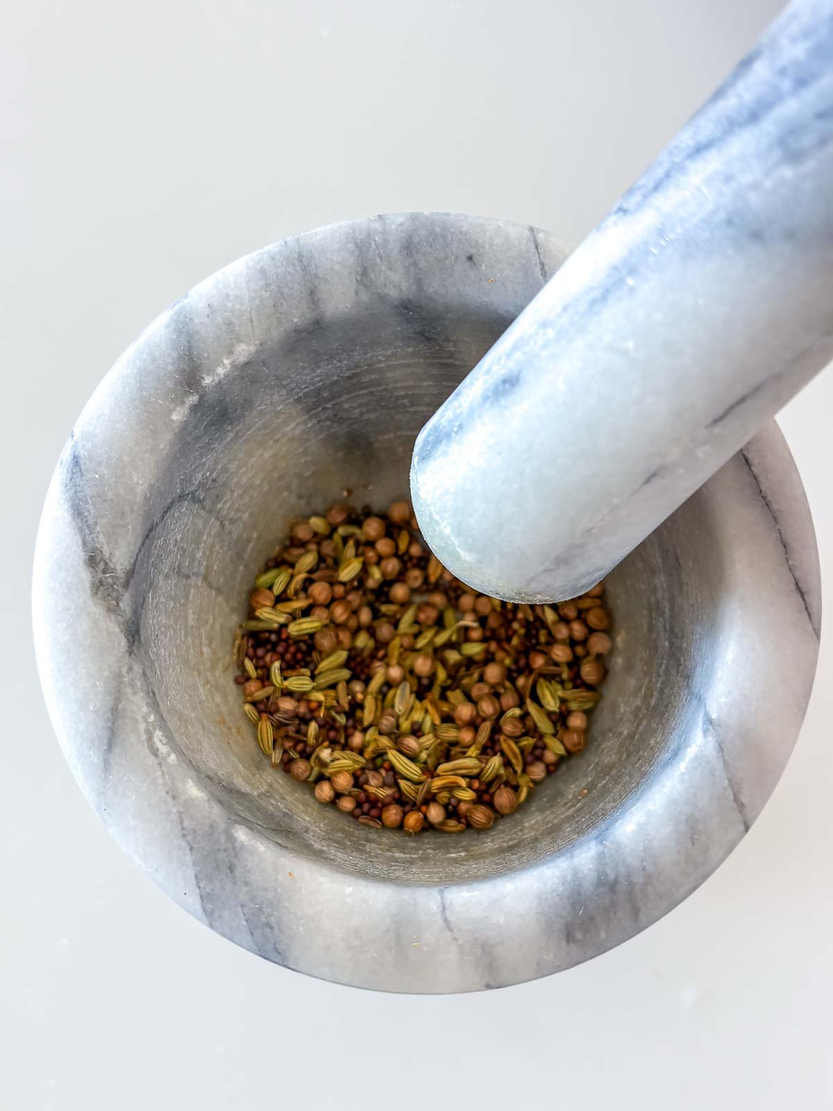 marble mortar and pestle with whole toasted spices. 